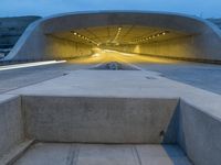 a large concrete bench and stairs in a tunnel with lights shining on the wall behind it