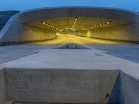 a large concrete bench and stairs in a tunnel with lights shining on the wall behind it