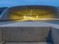 a large concrete bench and stairs in a tunnel with lights shining on the wall behind it
