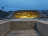 a large concrete bench and stairs in a tunnel with lights shining on the wall behind it