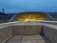 a large concrete bench and stairs in a tunnel with lights shining on the wall behind it