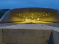 a large concrete bench and stairs in a tunnel with lights shining on the wall behind it