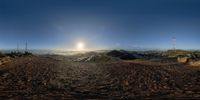 the sun is setting over a valley as a road goes through it with dirt in the foreground