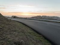 the person is riding their bicycle down the road while the sun sets over the water