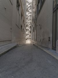 a narrow alley between two large building in the city with an empty bench at the end