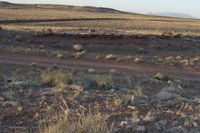 a person is riding on a horse in the dirt hill land next to the road