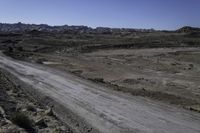 the dirt road is winding through a barren area surrounded by rocks and boulders along both sides