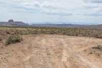 a motorcycle is driving through the desert on an empty road in a mountainous landscape with a sky