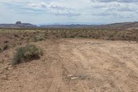 a motorcycle is driving through the desert on an empty road in a mountainous landscape with a sky