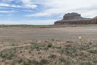 an empty field next to a big mountain with rocks in the background of the picture