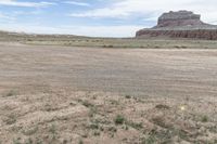 an empty field next to a big mountain with rocks in the background of the picture