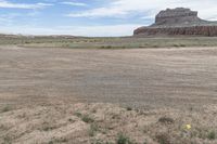 an empty field next to a big mountain with rocks in the background of the picture