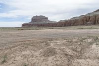 an empty field next to a big mountain with rocks in the background of the picture