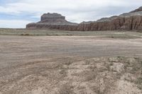 an empty field next to a big mountain with rocks in the background of the picture