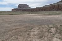 an empty field next to a big mountain with rocks in the background of the picture