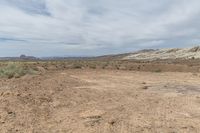 a large field is shown with desert land in the distance and a cloud above it