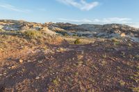 a view over a small area of rocky and bare grass, with dirt covered hill in background