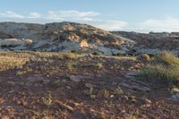 a view over a small area of rocky and bare grass, with dirt covered hill in background