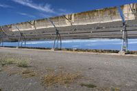 an old solar array with mirrors is shown in the desert side, near the road