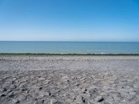 the empty beach is very deserted by the water with lots of gravel and rocks all around it