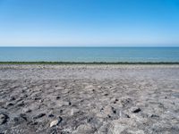 the empty beach is very deserted by the water with lots of gravel and rocks all around it