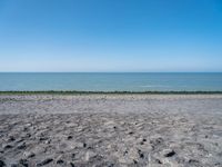 the empty beach is very deserted by the water with lots of gravel and rocks all around it