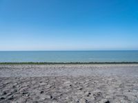 the empty beach is very deserted by the water with lots of gravel and rocks all around it