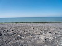 the empty beach is very deserted by the water with lots of gravel and rocks all around it