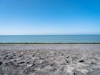 the empty beach is very deserted by the water with lots of gravel and rocks all around it