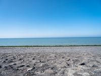 the empty beach is very deserted by the water with lots of gravel and rocks all around it