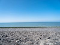 the empty beach is very deserted by the water with lots of gravel and rocks all around it