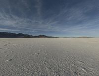 this is an image of a desert, with many tracks in the snow that lead to a huge mountain