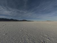 this is an image of a desert, with many tracks in the snow that lead to a huge mountain