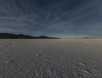 this is an image of a desert, with many tracks in the snow that lead to a huge mountain