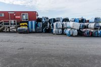 some pallets are stacked up outside a building while a man sits by the side of a road