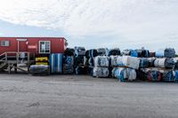 some pallets are stacked up outside a building while a man sits by the side of a road