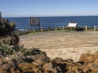 a bench on a mountain beside the ocean and a sign showing where to park for visitors