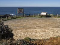 a bench on a mountain beside the ocean and a sign showing where to park for visitors