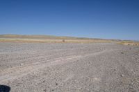 a motorcycle parked in the middle of an empty road in the desert setting, with a few other vehicles and vehicle in the distance