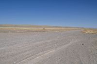 a motorcycle parked in the middle of an empty road in the desert setting, with a few other vehicles and vehicle in the distance