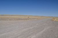 a motorcycle parked in the middle of an empty road in the desert setting, with a few other vehicles and vehicle in the distance