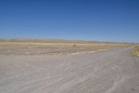 a motorcycle parked in the middle of an empty road in the desert setting, with a few other vehicles and vehicle in the distance