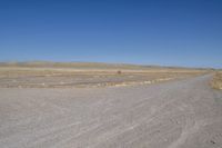 a motorcycle parked in the middle of an empty road in the desert setting, with a few other vehicles and vehicle in the distance