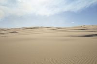 a person walks across a dune field near some tall dunes with sand dunes on top of it