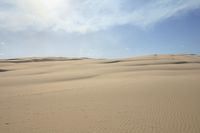 a person walks across a dune field near some tall dunes with sand dunes on top of it