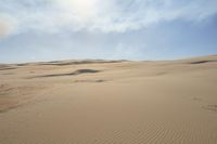 a person walks across a dune field near some tall dunes with sand dunes on top of it