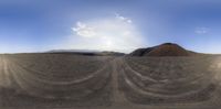 some sand mountains and a blue sky with clouds over them and a plane is flying