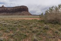 a white truck sitting in the middle of a dirt road and in the distance, an out of focus rock