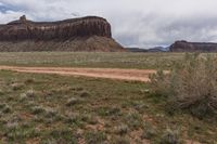 a white truck sitting in the middle of a dirt road and in the distance, an out of focus rock