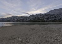 a sandy beach near the shore in the mountains, on a cloudy day with mountains behind